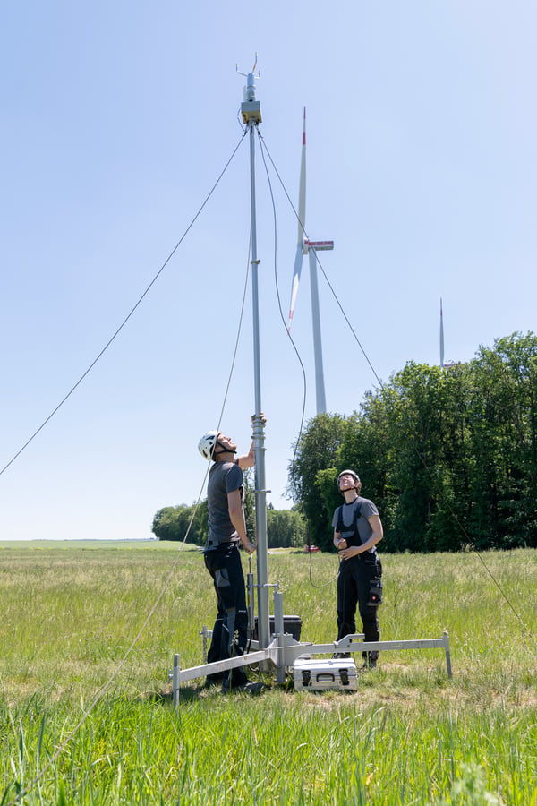 Windmessmast mit Windenergieanlage im Hintergrund